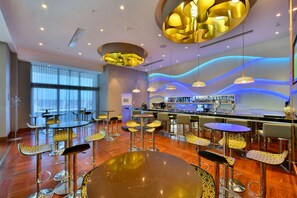 A modern bar area with multiple seating options, including high stools and round tables.