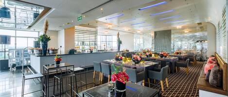A modern restaurant with a bar area, seating arrangements, and decorative plants.