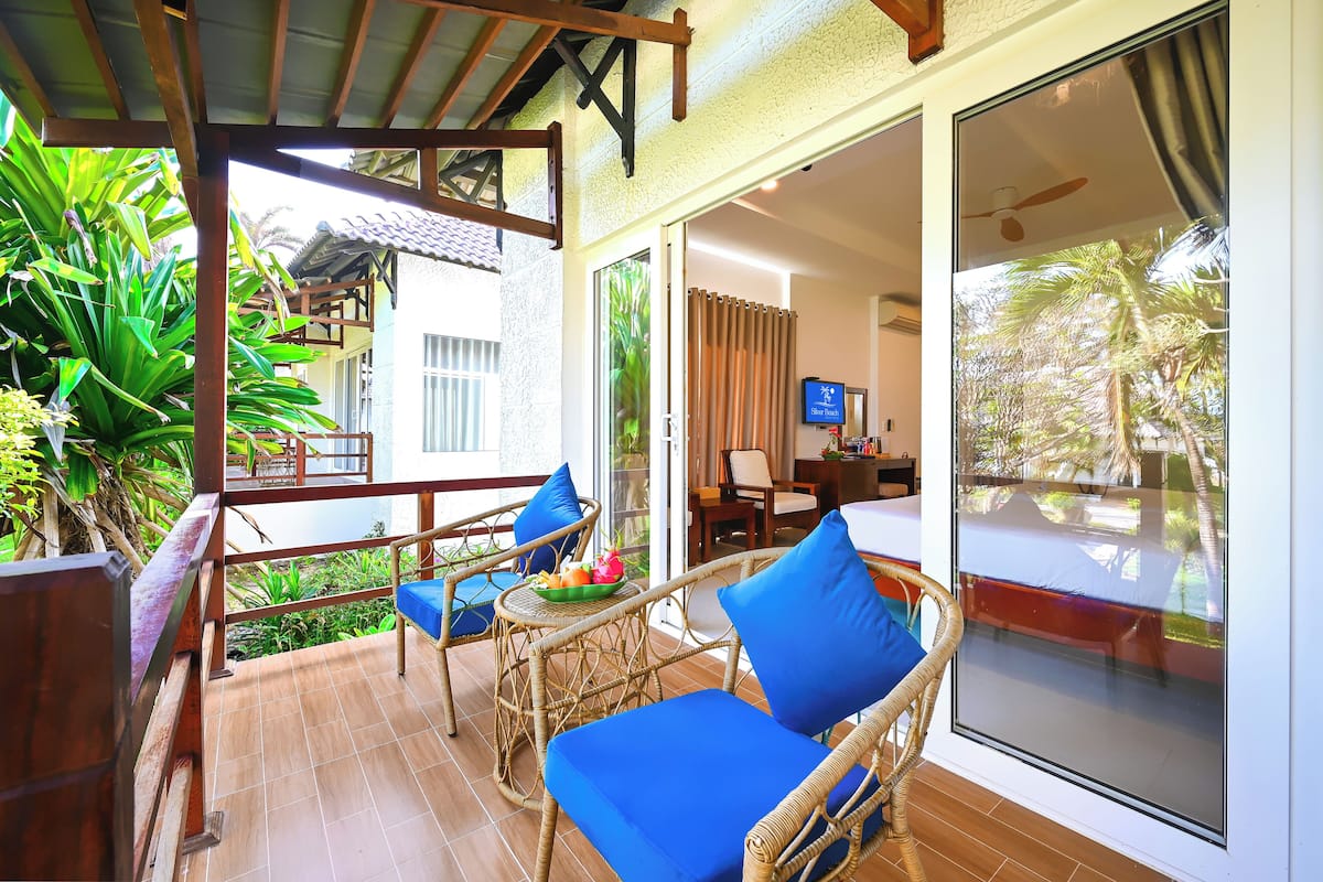 A balcony with wicker furniture, a dining area, and a TV.