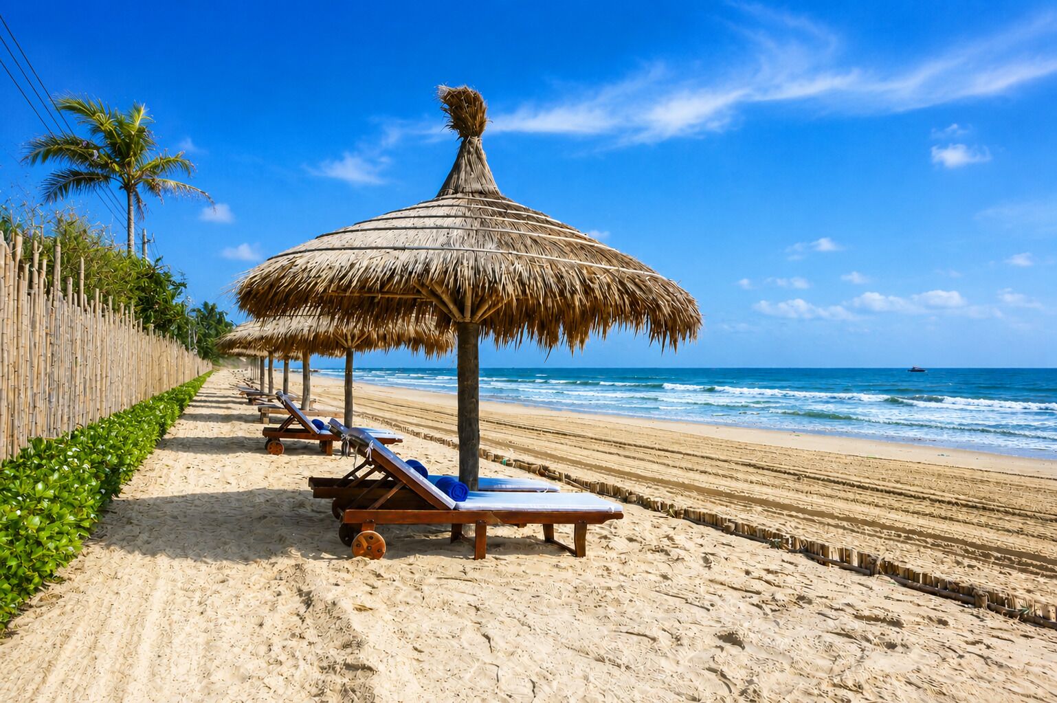 A beach with thatched umbrellas and sun loungers along the shore.