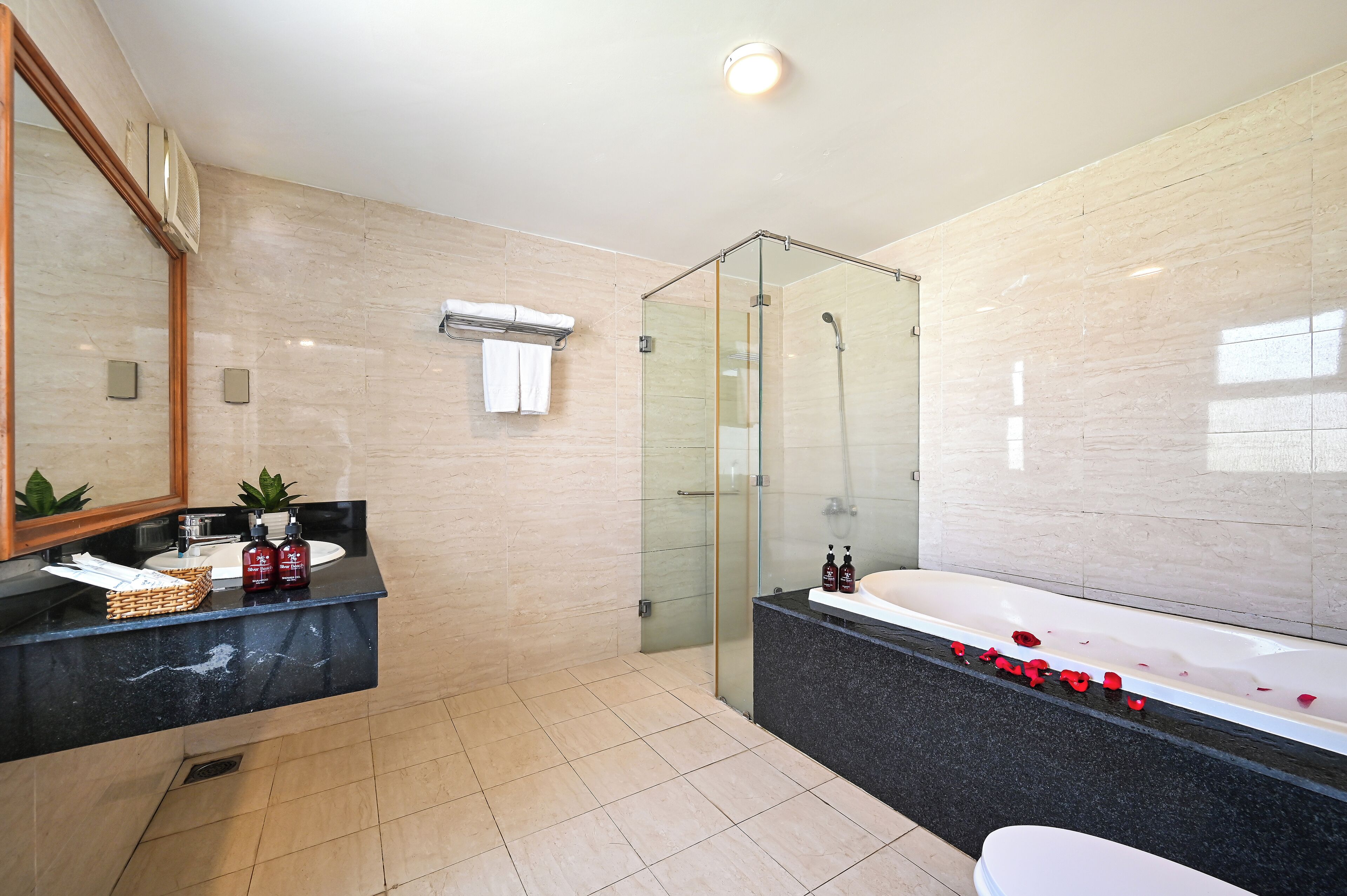 A modern bathroom with a glass-enclosed shower, a large bathtub, and a vanity with a marble countertop.