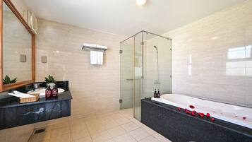 A modern bathroom with a glass-enclosed shower, a large bathtub, and a vanity with a marble countertop.