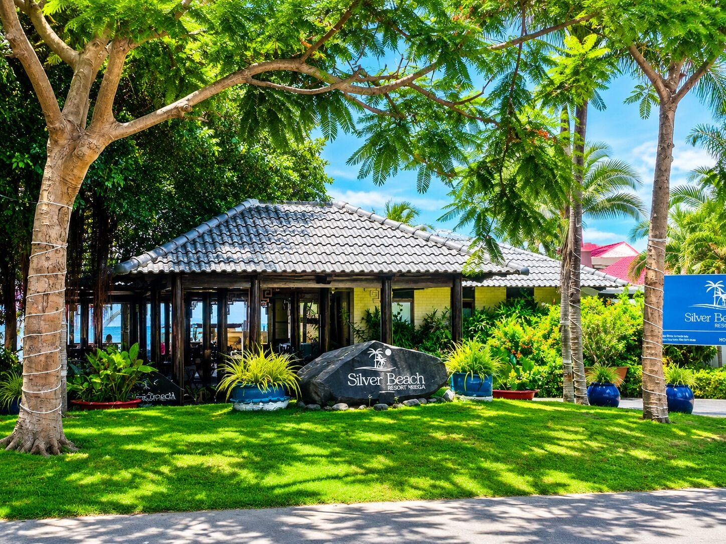 Un resort con techo de tejas, rodeado de exuberante vegetación y palmeras.