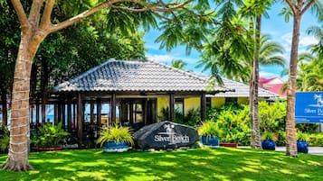 Un resort con techo de tejas, rodeado de exuberante vegetación y palmeras.