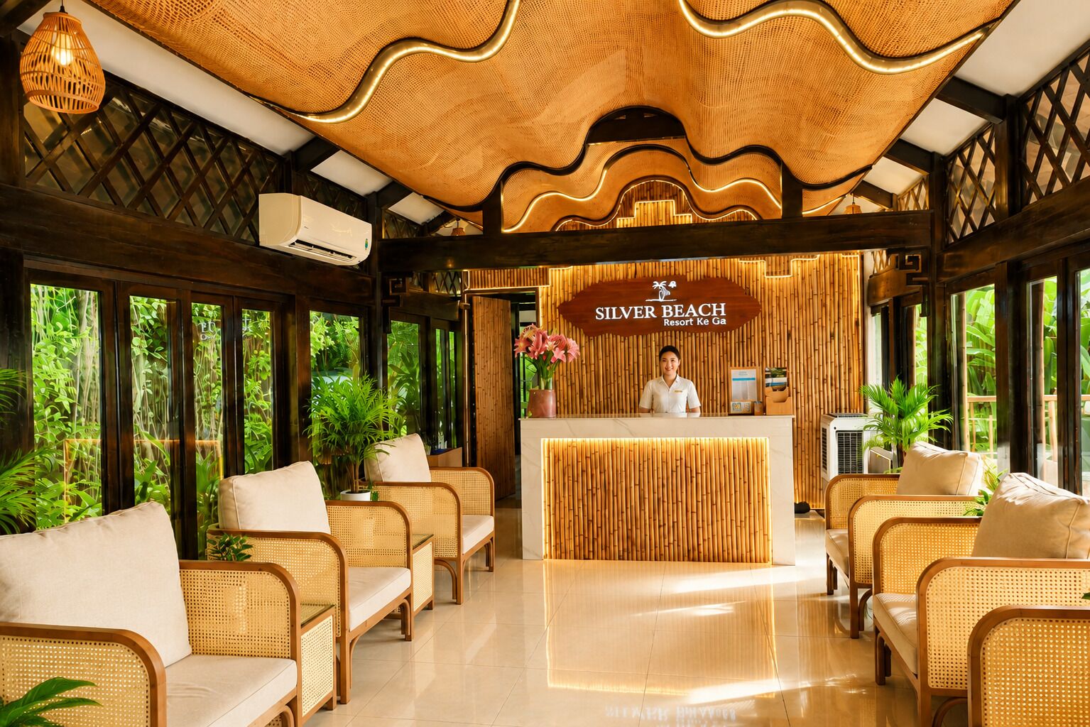 Un espace d’accueil doté d’un plafond en bambou, de meubles en osier et d’une enseigne indiquant le « Silver Beach Resort ».