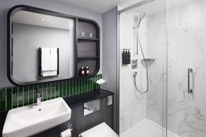 A modern bathroom with a large mirror, a sink, a shower, and a green-tiled backsplash. - Residence Inn by Marriott Manchester Piccadilly (Manchester)