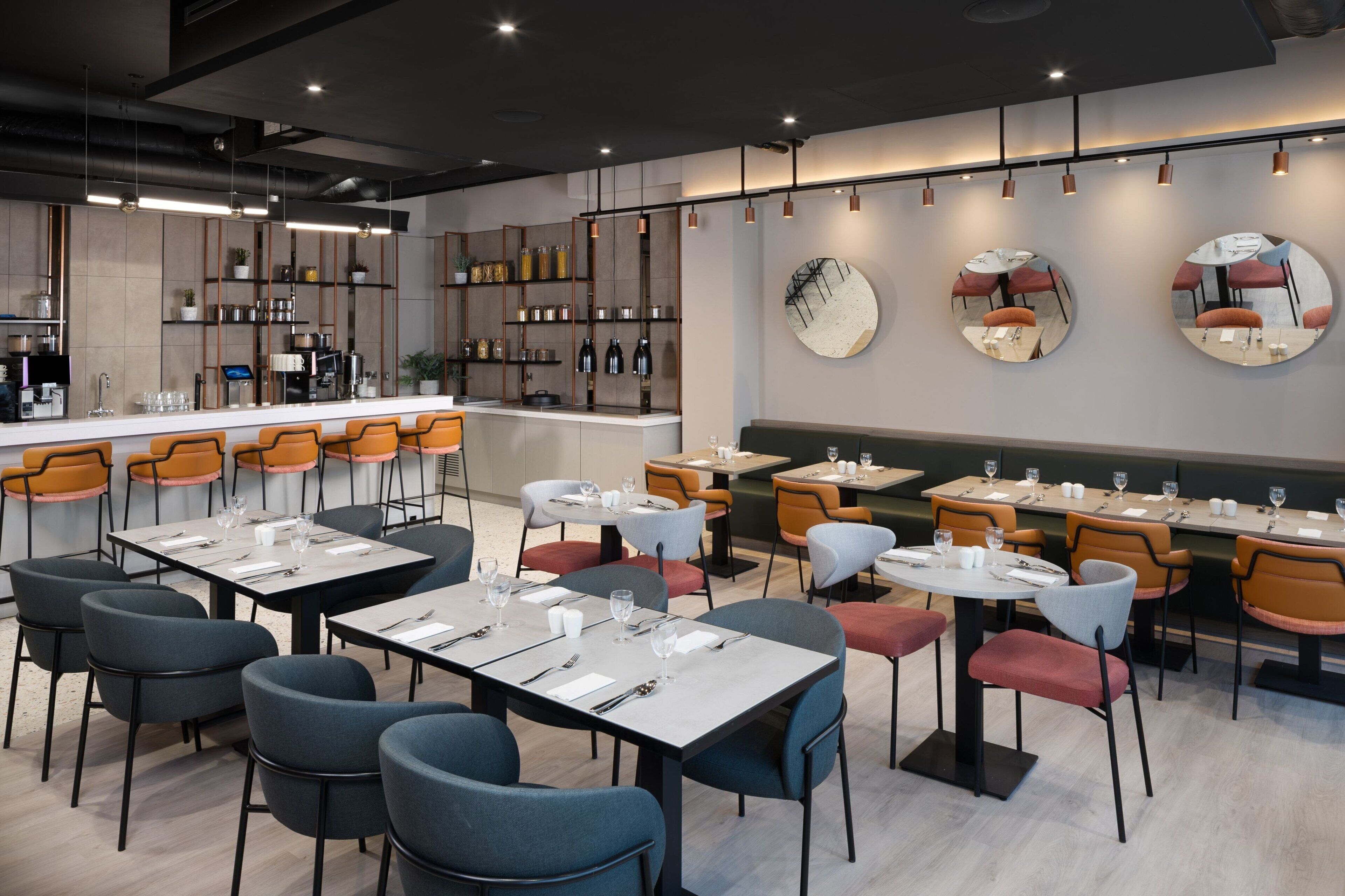 Un restaurant modern amb una zona de bar, diverses taules i seients.