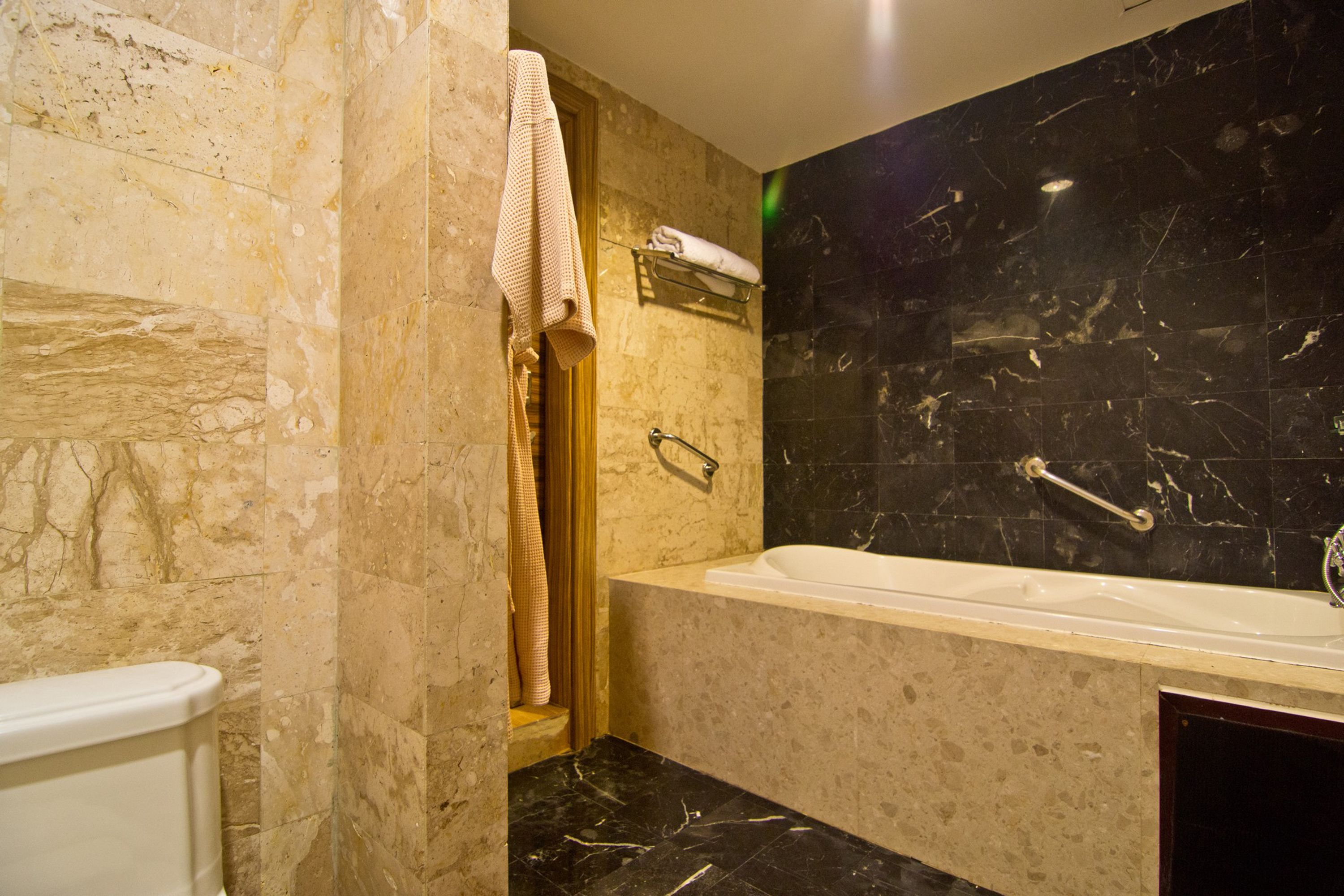 A bathroom with a bathtub, a towel rack, and a toilet.