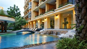 Un hôtel doté d’une piscine, d’un espace extérieur aménagé et d’une cascade décorative.