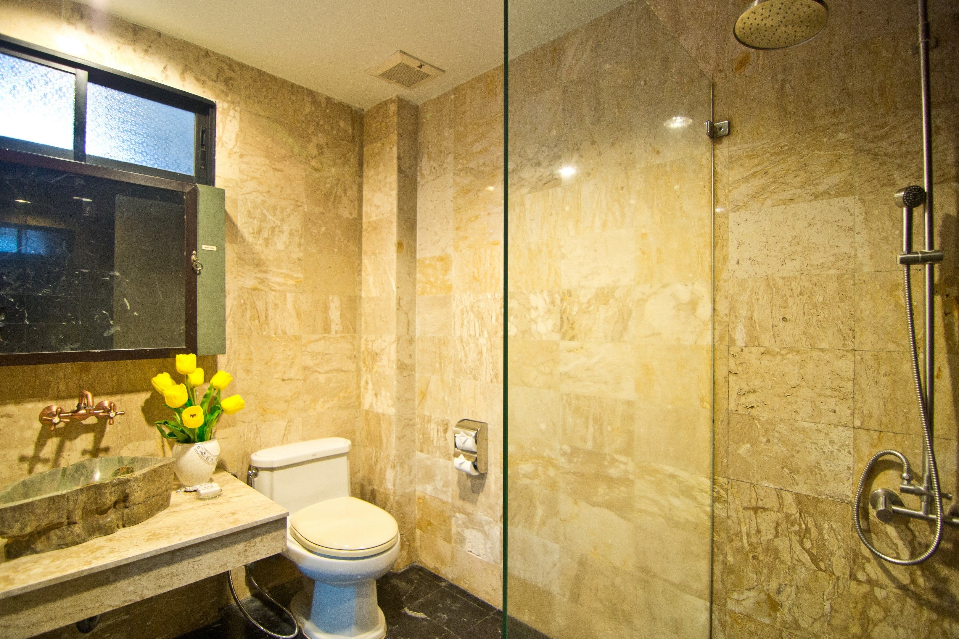 Baño con lavamanos, inodoro y zona de ducha de mármol.