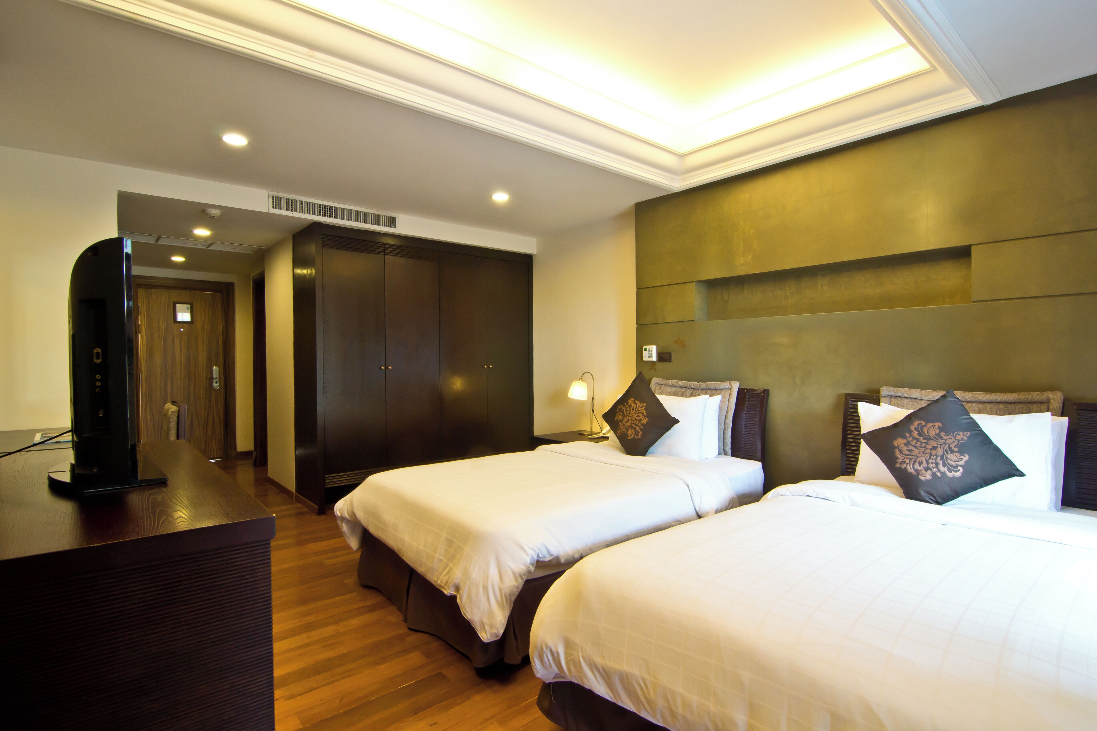 Une chambre d’hôtel avec deux lits, un bureau, une armoire et un téléviseur.