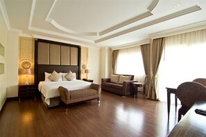 A spacious hotel room with a large bed, a sofa, a desk, and a view of the outdoors. - LK Residence (Pattaya)