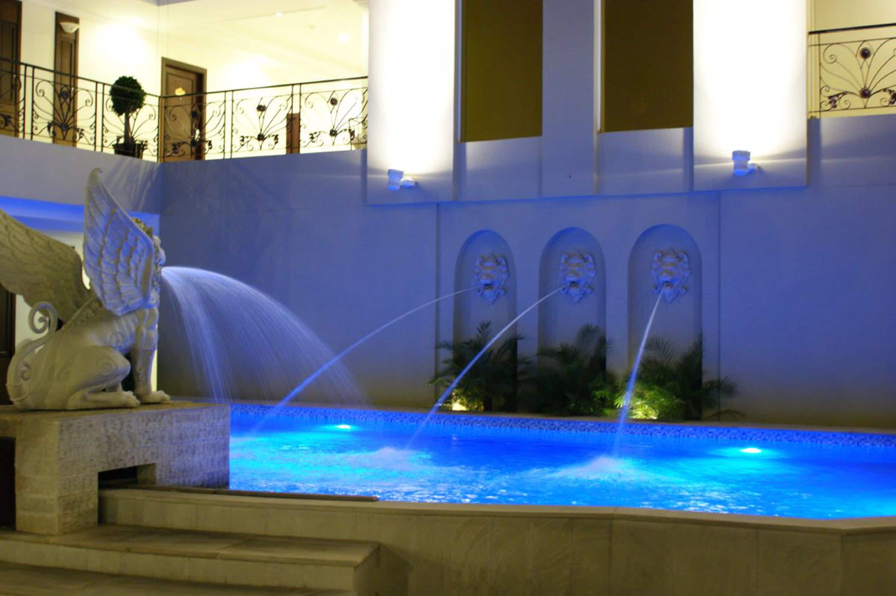 A fountain with water jets and a statue of a winged creature.