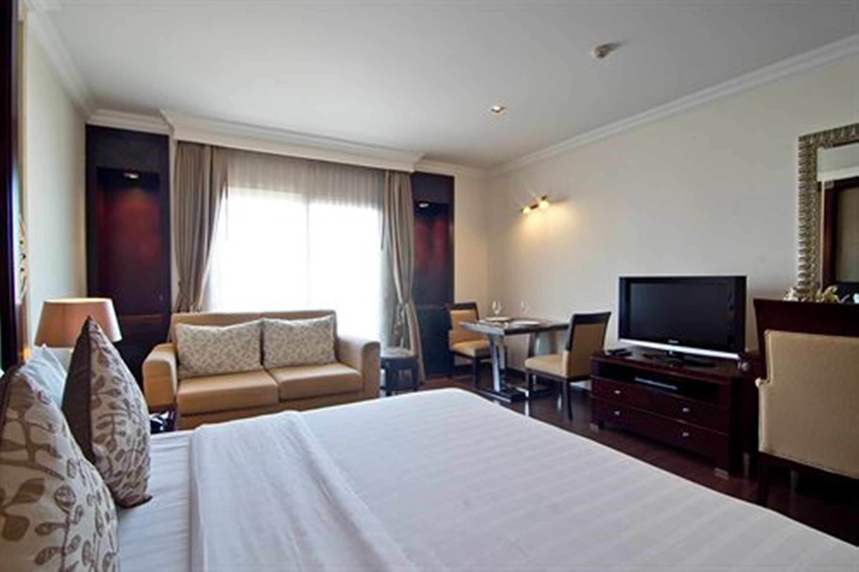 Een hotelkamer met een groot bed, een bank, een bureau en een televisie.