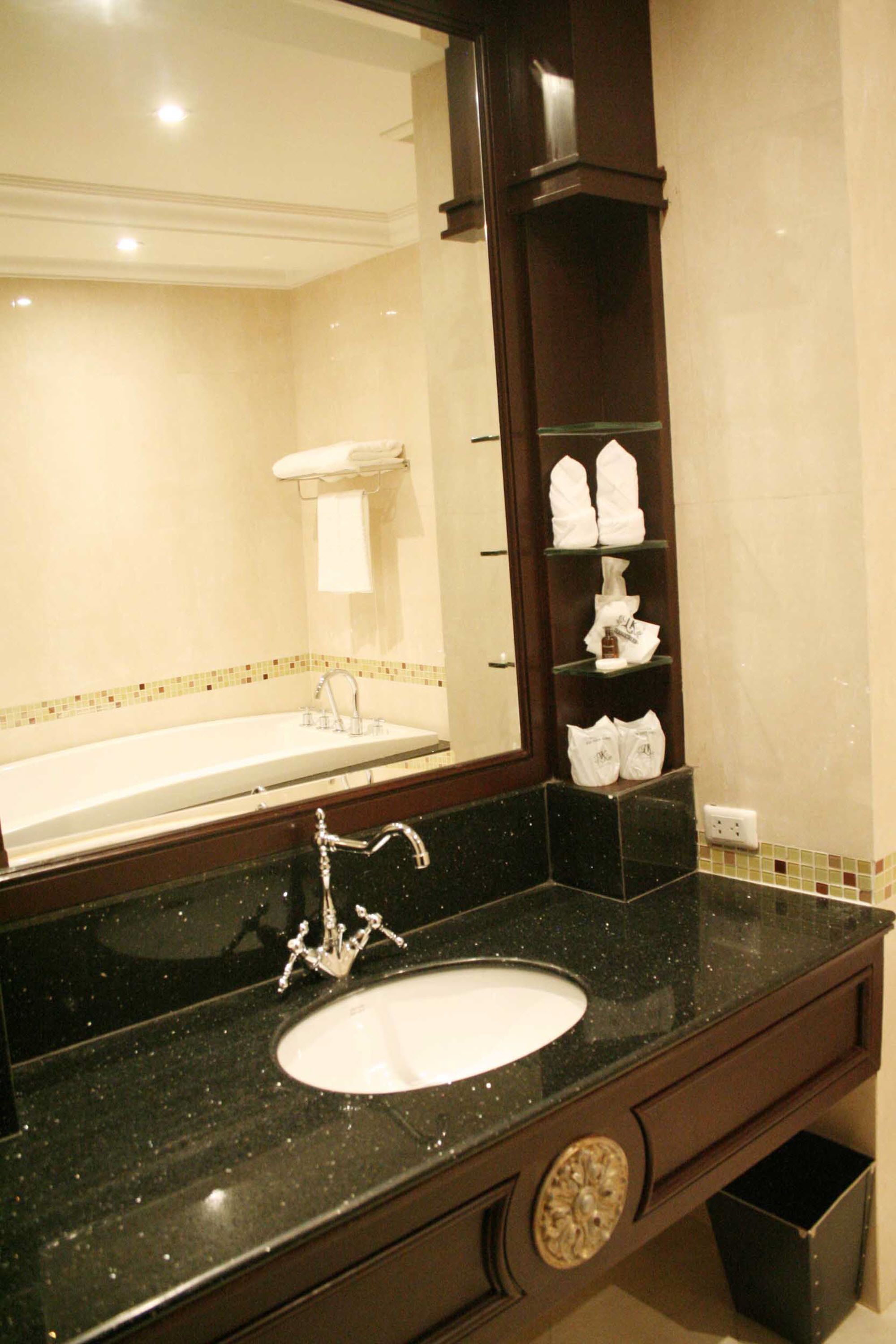 A bathroom with a large mirror, a sink, and a towel rack.