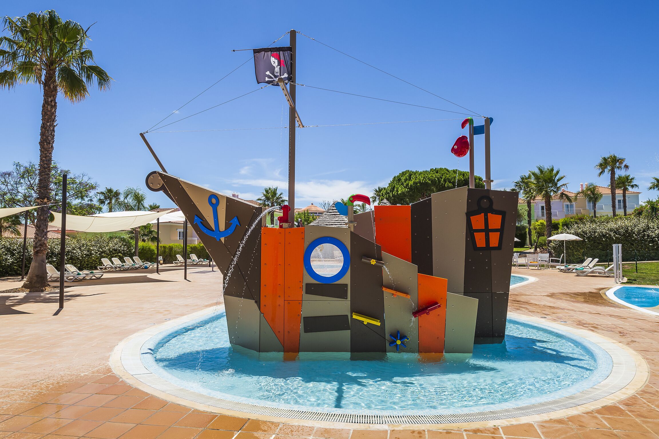 Une fontaine aquatique sur le thème des pirates, agrémentée d’un drapeau, d’une bouée de sauvetage et d’un gouvernail de navire.