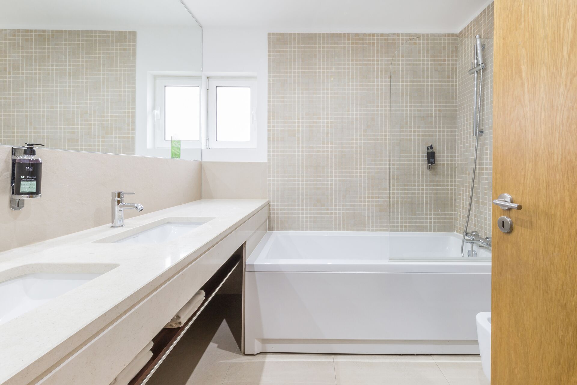 A modern bathroom with two sinks, a bathtub, and a shower.
