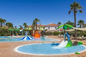 A swimming pool area with slides and water features, surrounded by palm trees and lounge chairs. - Eden Villas & Apartments (Albufeira)