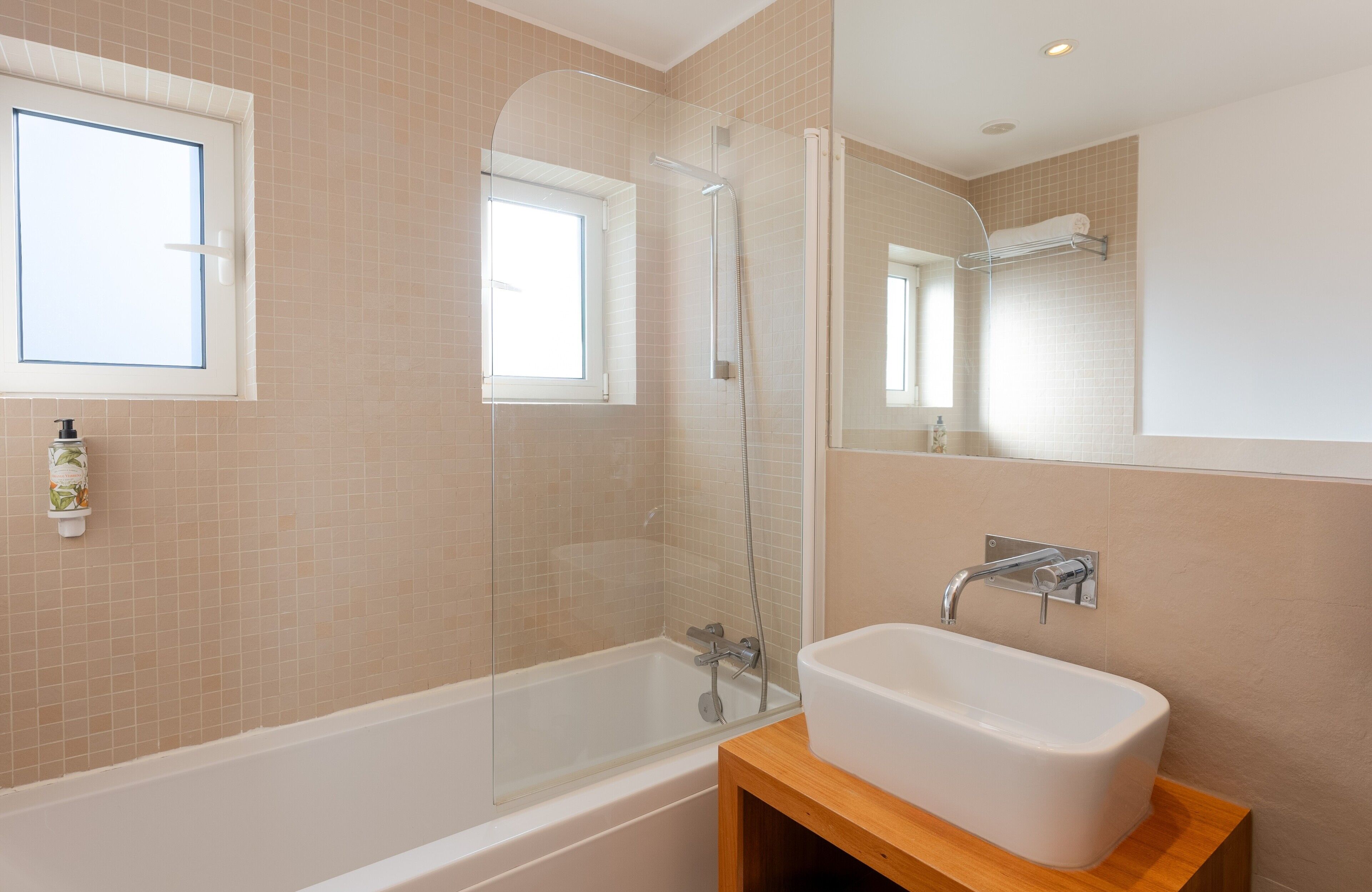Een moderne badkamer met een bad, douchecabine, wastafel en een raam.