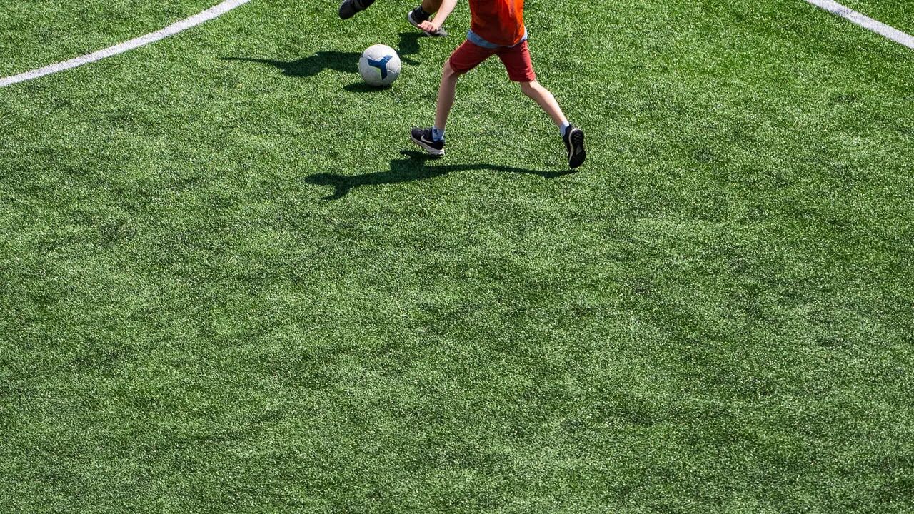 Una persona jugando al fútbol en un campo verde.