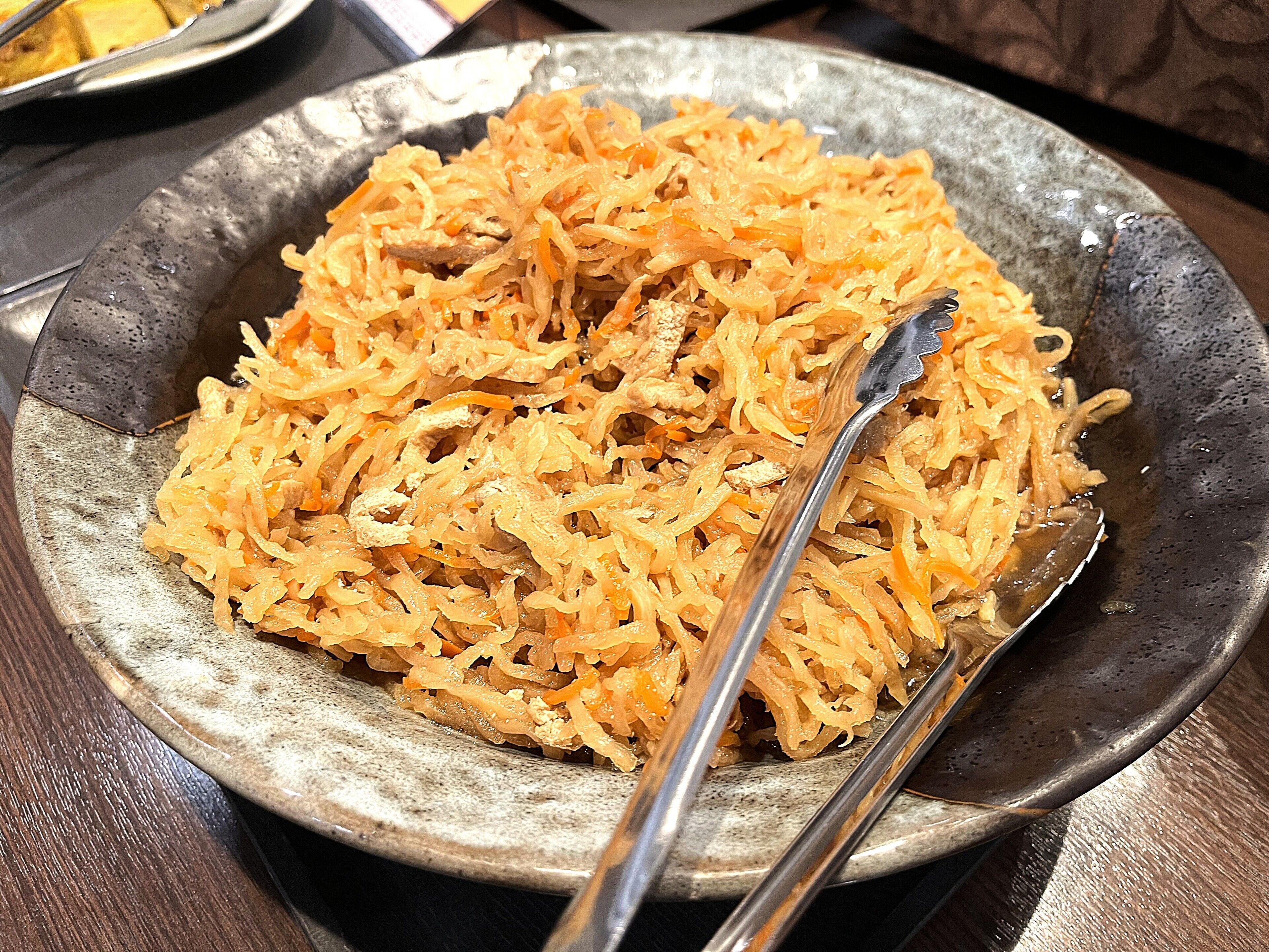 A bowl of shredded food with a spoon.