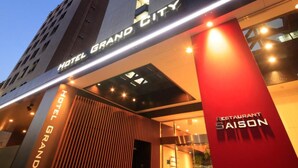 A modern hotel entrance with a prominent vertical sign reading "HOTEL GRAND CITY" and a red pillar with "RESTAURANT SAISON" on it. - Hotel Grand City (Tokyo)