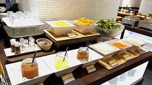 A buffet setup with various food items, including fruits, salads, and condiments. - Hotel Grand City (Tokyo)