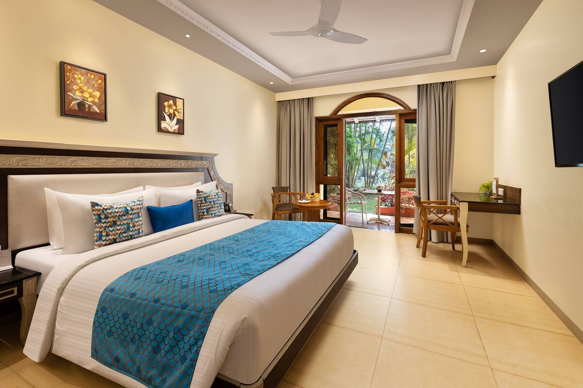 A hotel room with a large bed, a desk, and a view of the outdoors.