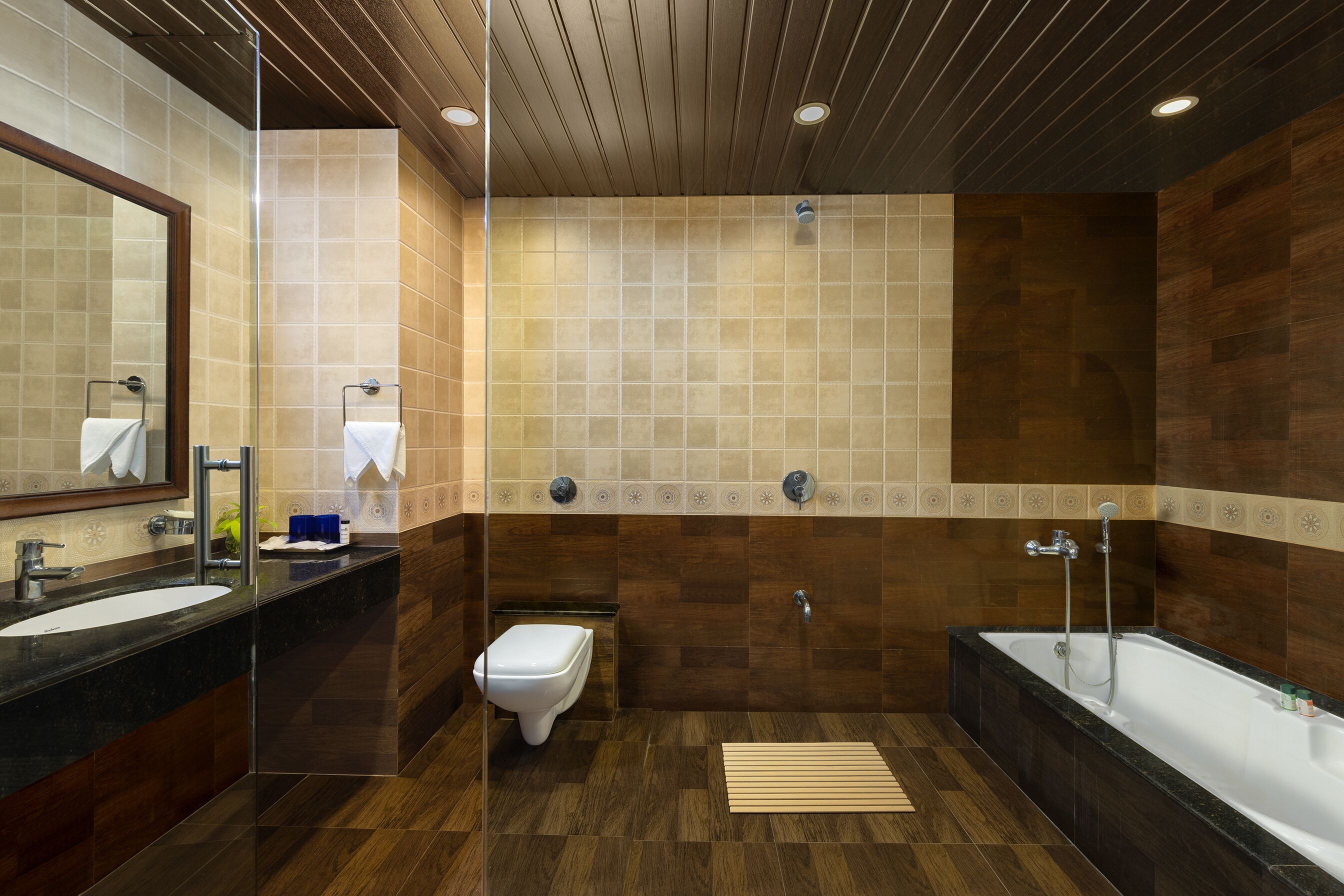 A modern bathroom with a large mirror, a toilet, a sink, and a bathtub.