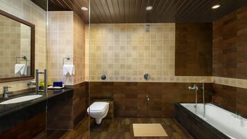 A modern bathroom with a large mirror, a toilet, a sink, and a bathtub.