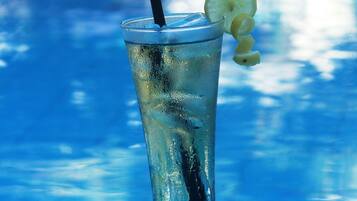 A tall glass with a straw and a slice of lime on a poolside table.