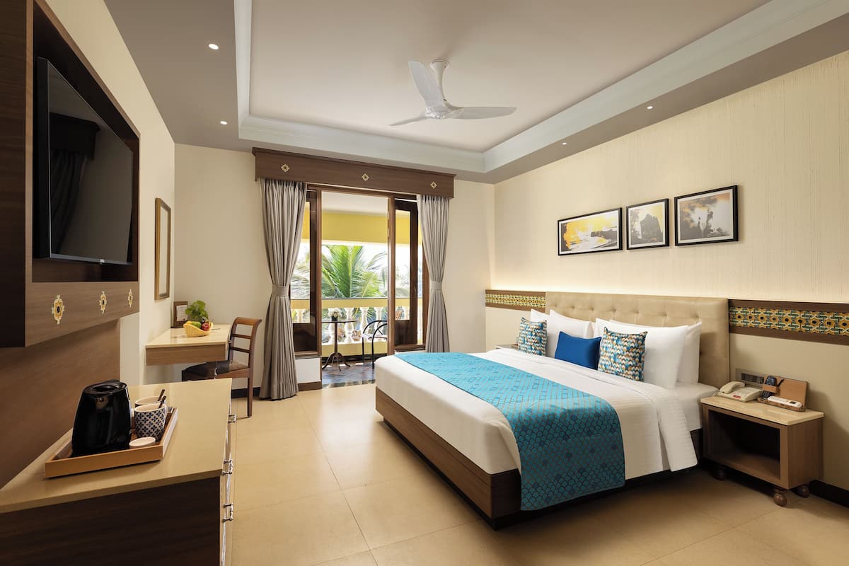 A hotel room with a bed, bedside table, TV, and a balcony with curtains.