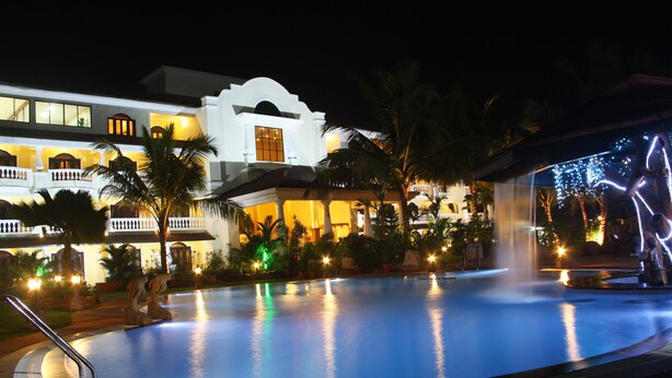 A swimming pool surrounded by palm trees and a building with balconies. - Fortune Resort Benaulim Goa - Member ITC Hotels' Group (Benaulim)