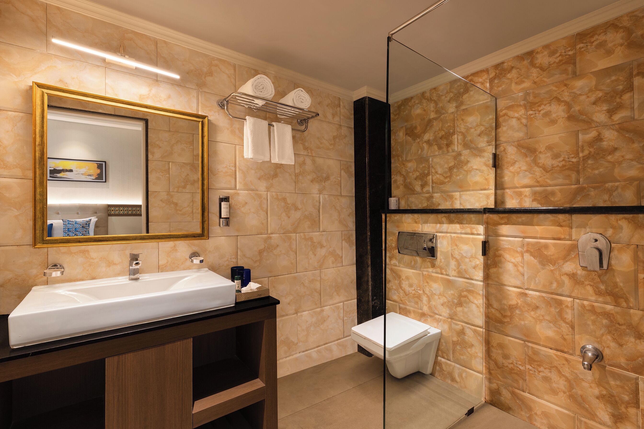 Un baño moderno con un espejo grande, un lavabo, un inodoro y una zona de ducha.