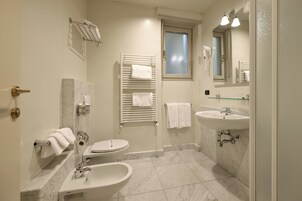 Un bagno con il water, bidet, lavandino e portasciugamani.