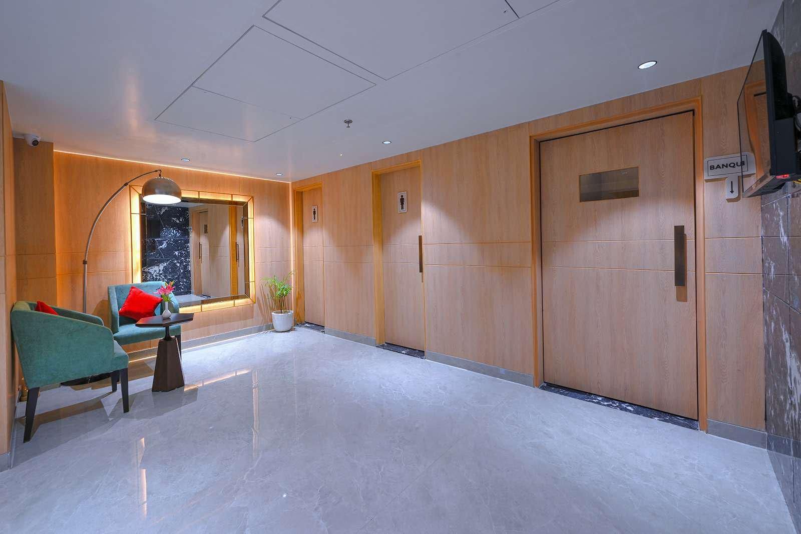 A hotel lobby with a reception desk, seating area, and a large wooden door marked 'BANQUE'.