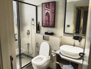 A modern bathroom with a glass shower enclosure, a toilet, and a sink with a mirror above.