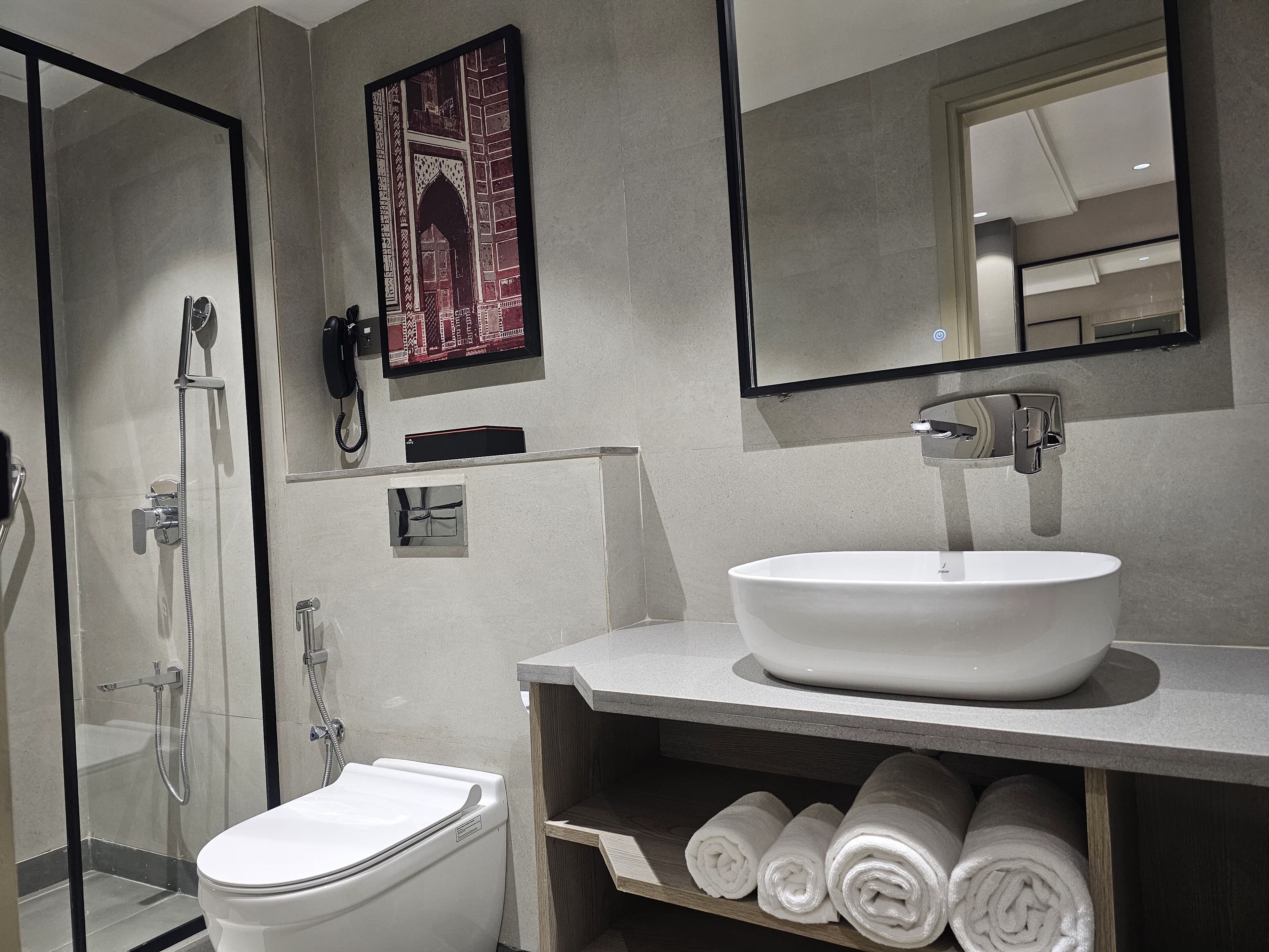 Un baño moderno con un lavabo blanco, cabina de ducha de vidrio y un inodoro.