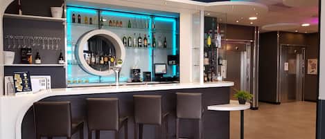 Un área de bar moderna con una barra curva, taburetes y estantes llenos de botellas y vasos.