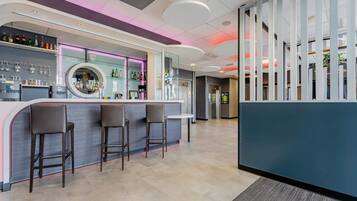 A modern bar area with a curved counter, bar stools, and a variety of bottles and glasses on shelves.
