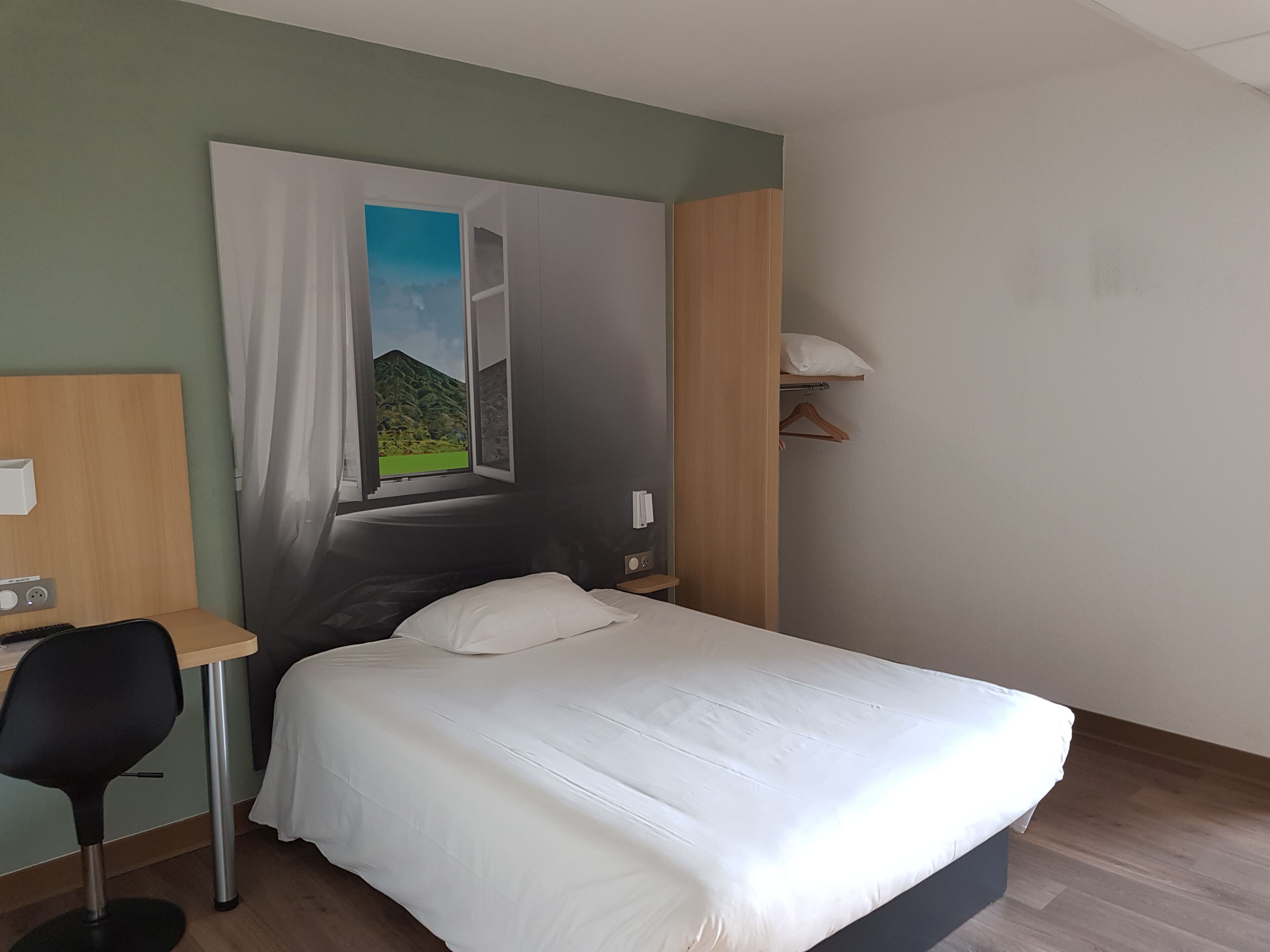 A bedroom with a bed, a desk, and a chair.
