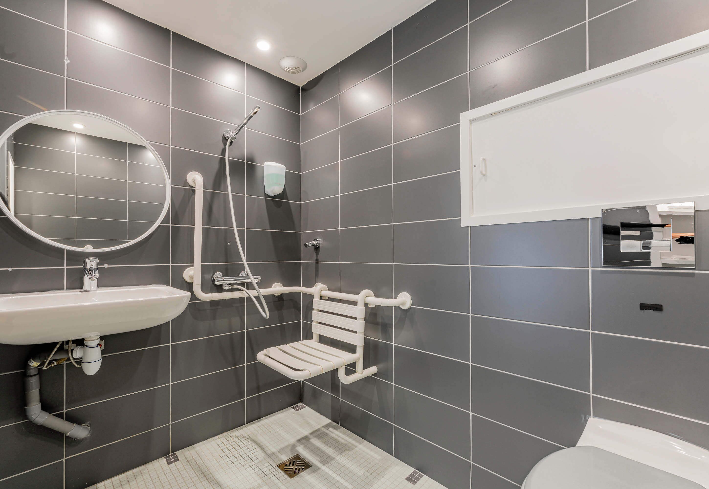 A modern bathroom with a white sink, mirror, and toilet.
