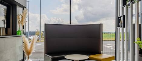 A modern interior with a seating area, large windows, and a view of the outside.