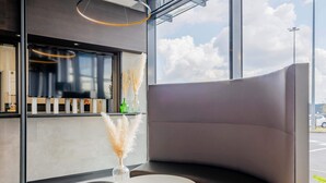 A modern interior with a curved seating area, a round table, and a window with a view of the sky. - B&B HOTEL Béthune Bruay-la-Buissière (Bruay-la-Buissiere)