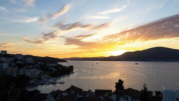 A coastal town at sunset with buildings along the waterfront and boats in the water.