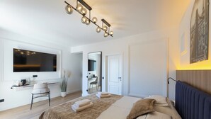 Un dormitorio moderno con una cama grande, un televisor en la pared, un escritorio con una silla y un espejo.