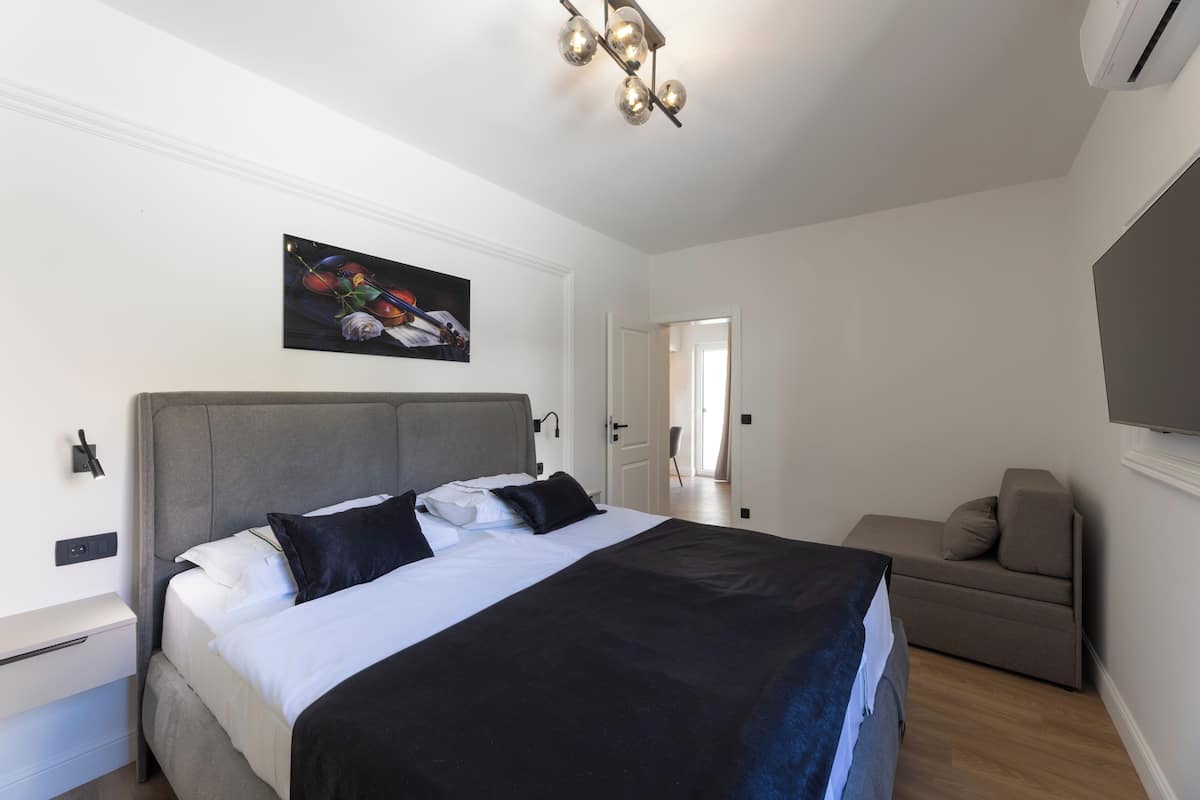 Quarto com cama, mesa de cabeceira e um quadro na parede.