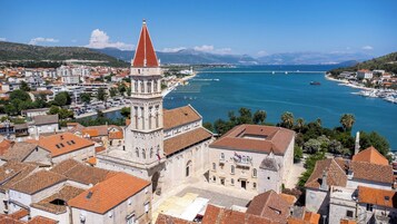 Un pueblo costero con arquitectura histórica, que incluye una torre destacada y un puerto deportivo frente al mar.