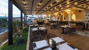 Un restaurante al aire libre con mesas y sillas, un muro de ladrillo y vistas a la ciudad.