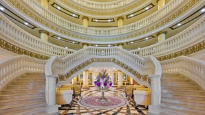A grand, multi-level atrium with ornate railings and a central floral arrangement.